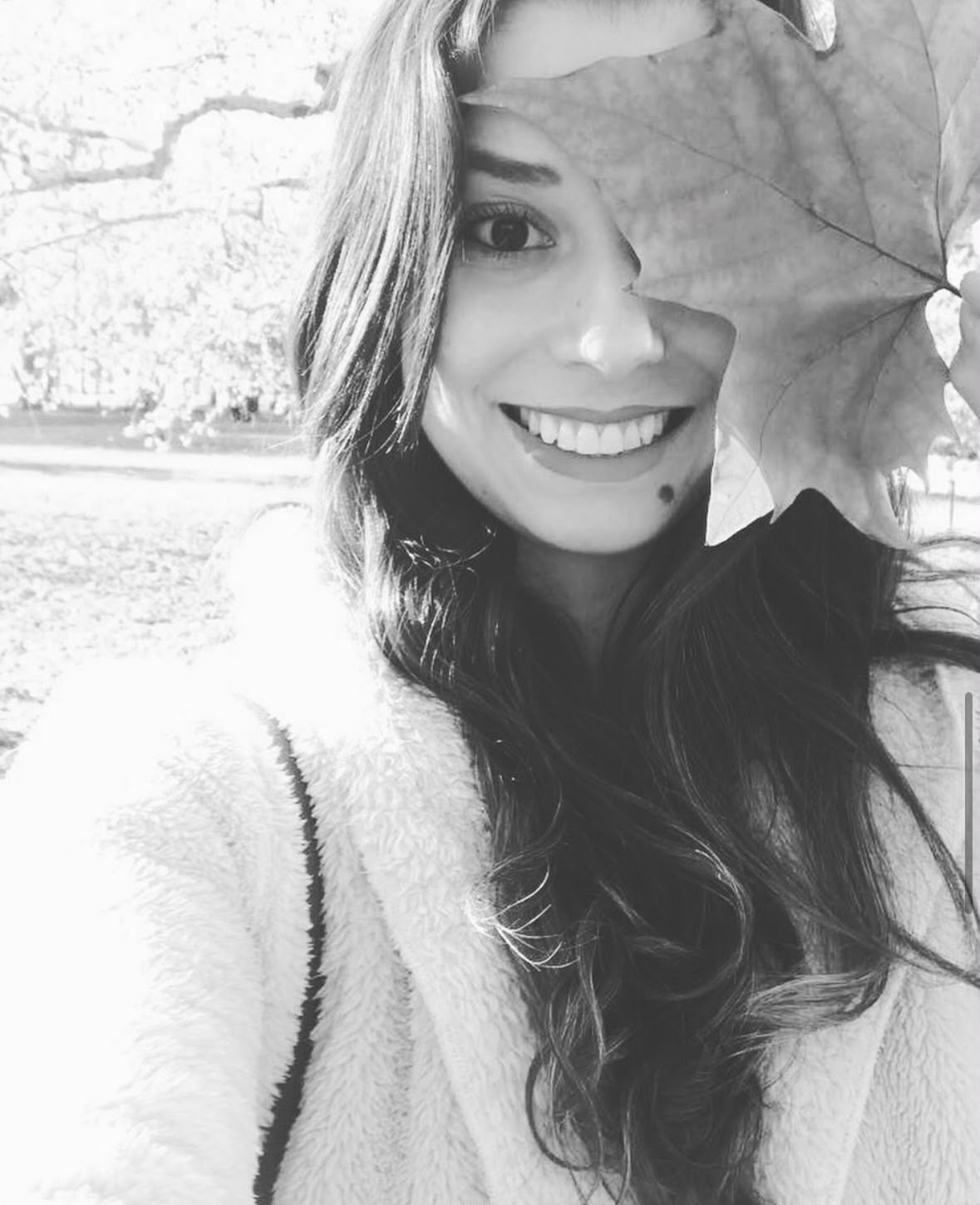 Rejane Rispoli sorrindo, com uma folha de outono cobrindo parte do rosto