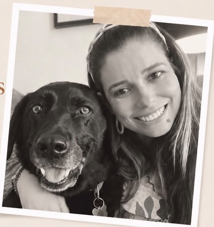 Rejane abraçada ao seu cachorro, em foto preto e branco estilo polaroid